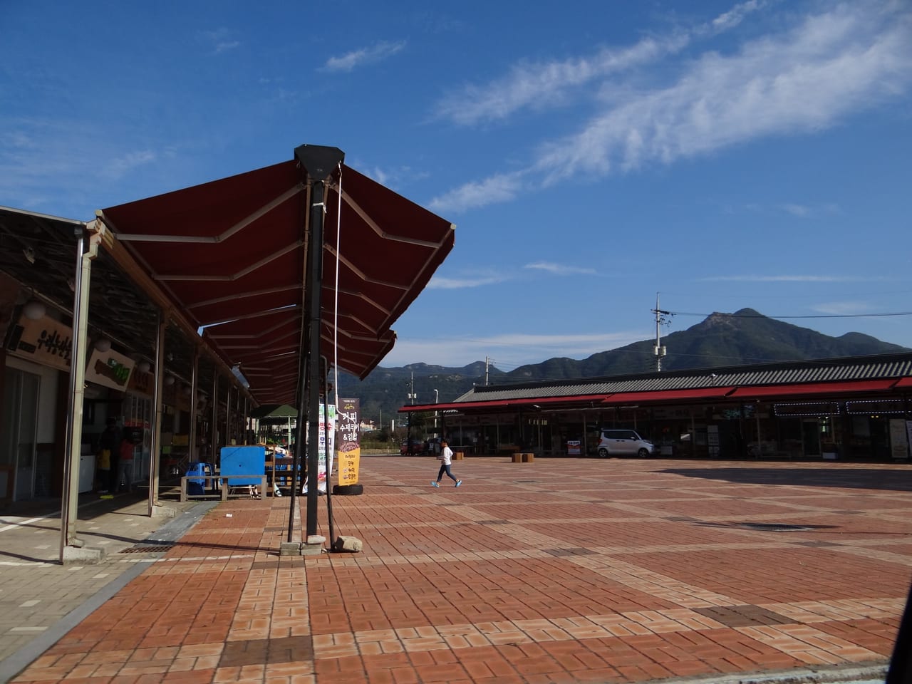 붉은 차양을 친 점포가 줄지어 선 고산미소시장의 붉은 벽돌 광장과 뒤로 솟은 산봉우리