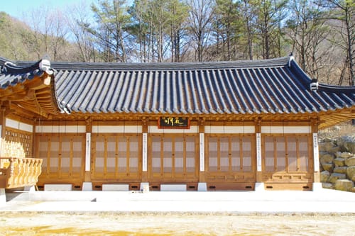 단청 없이 나무 빛깔을 살린 풍류학교 한옥 건물과 앞마당